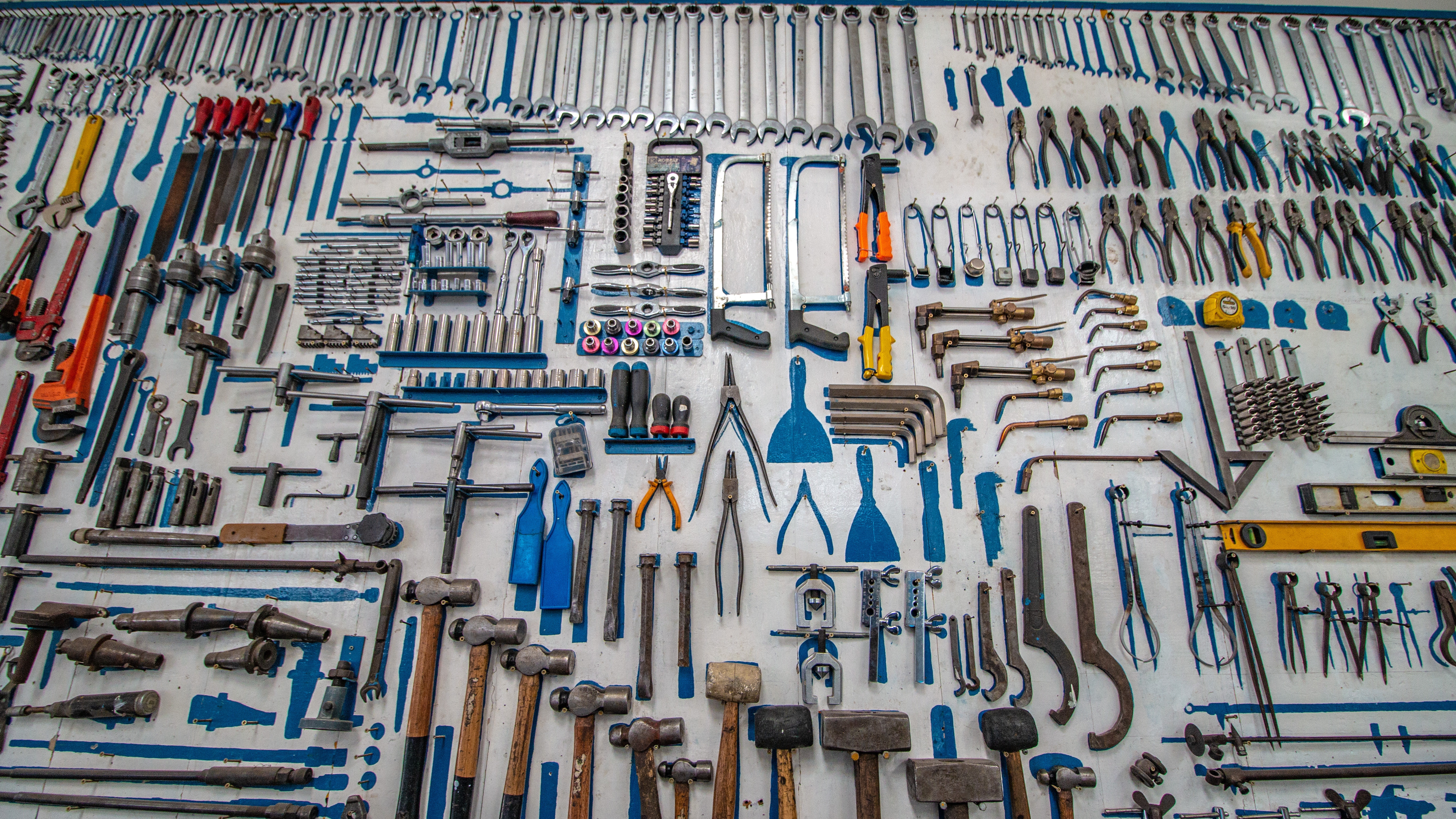 Tools on a workbench Multiple multi-colored handheld tools lined up on a work bench.