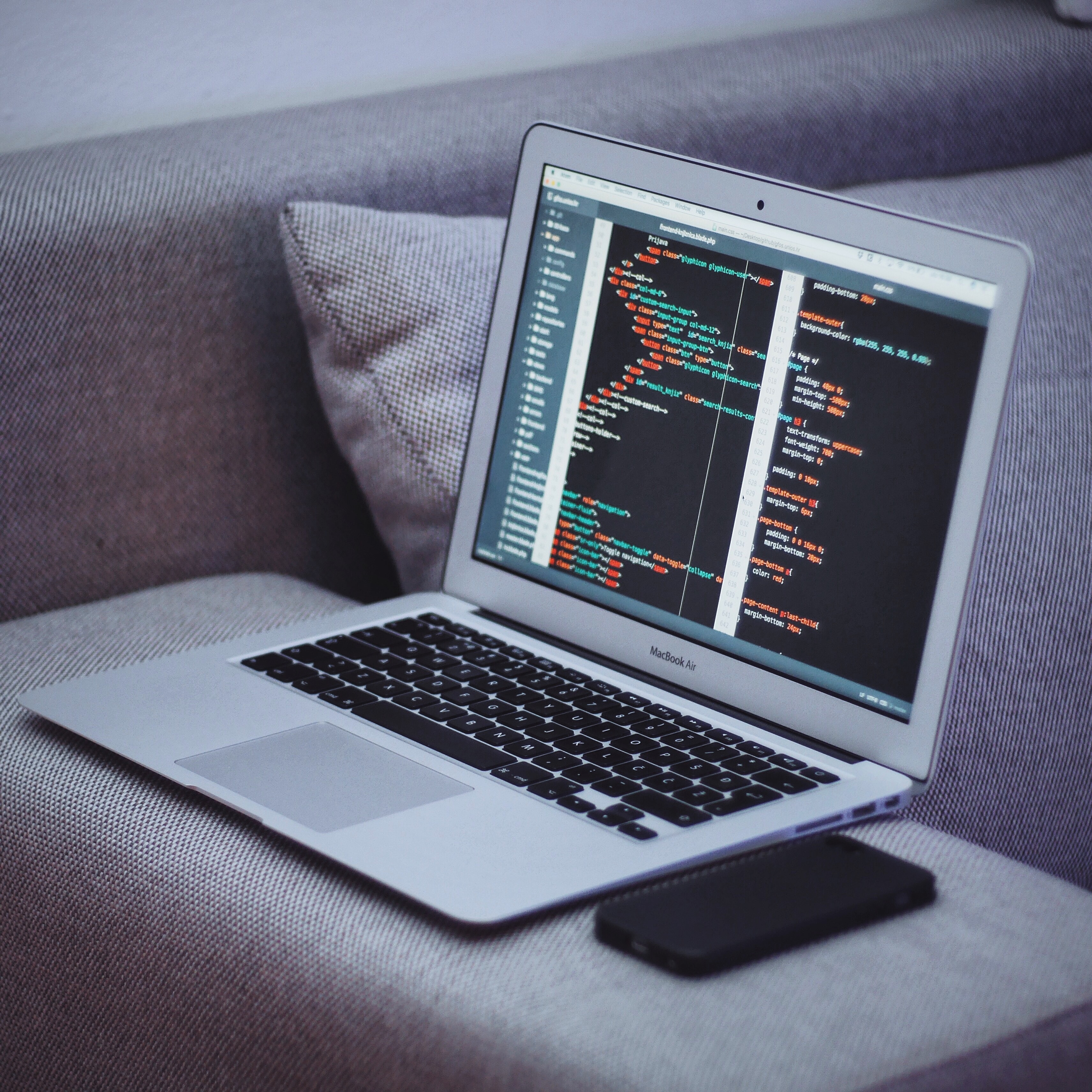 Laptop on an arm chair Laptop with code on a grey arm chair