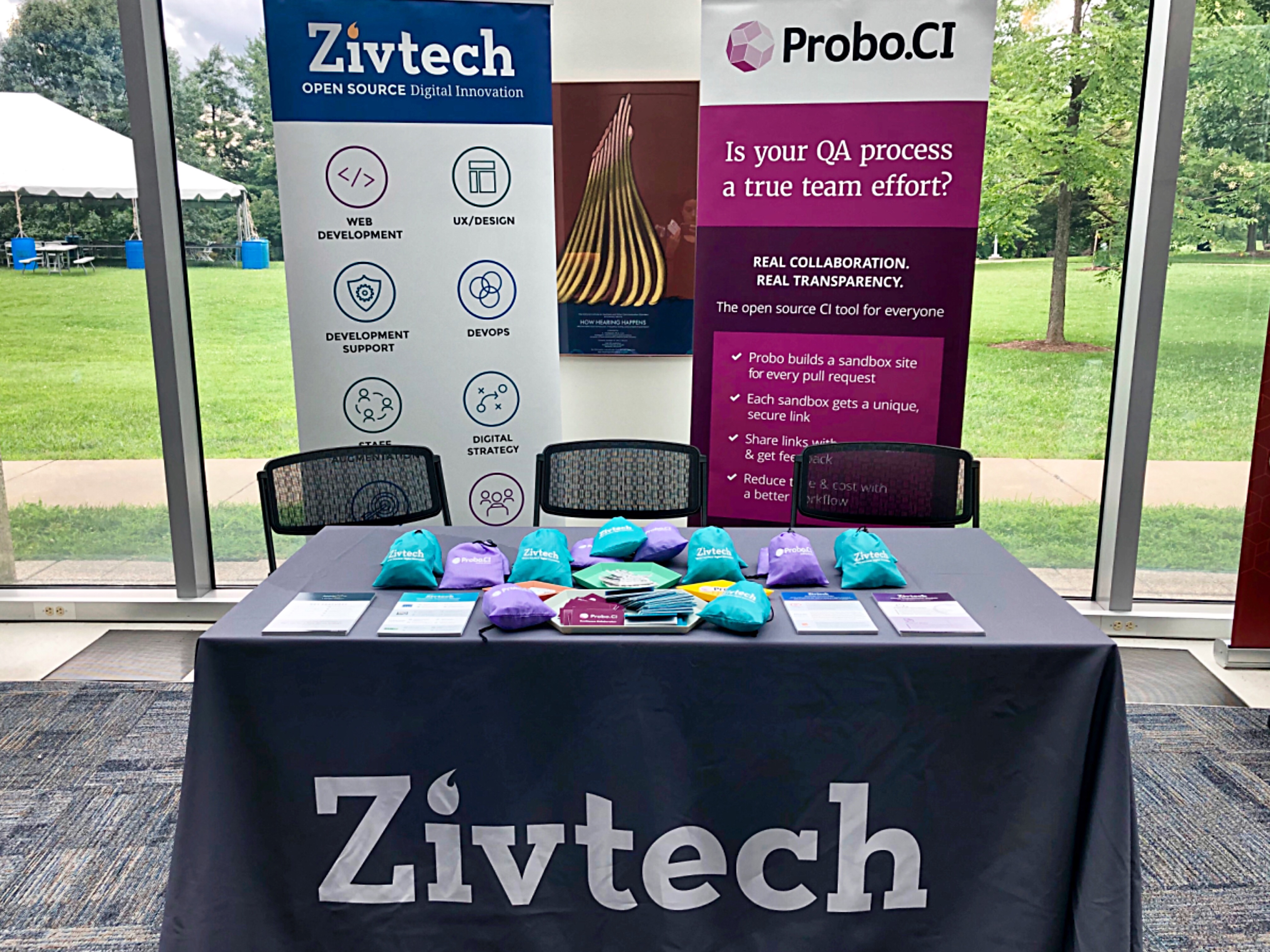 Conference table with grey table cloth, two pull-up banners, and other marketing materials. 